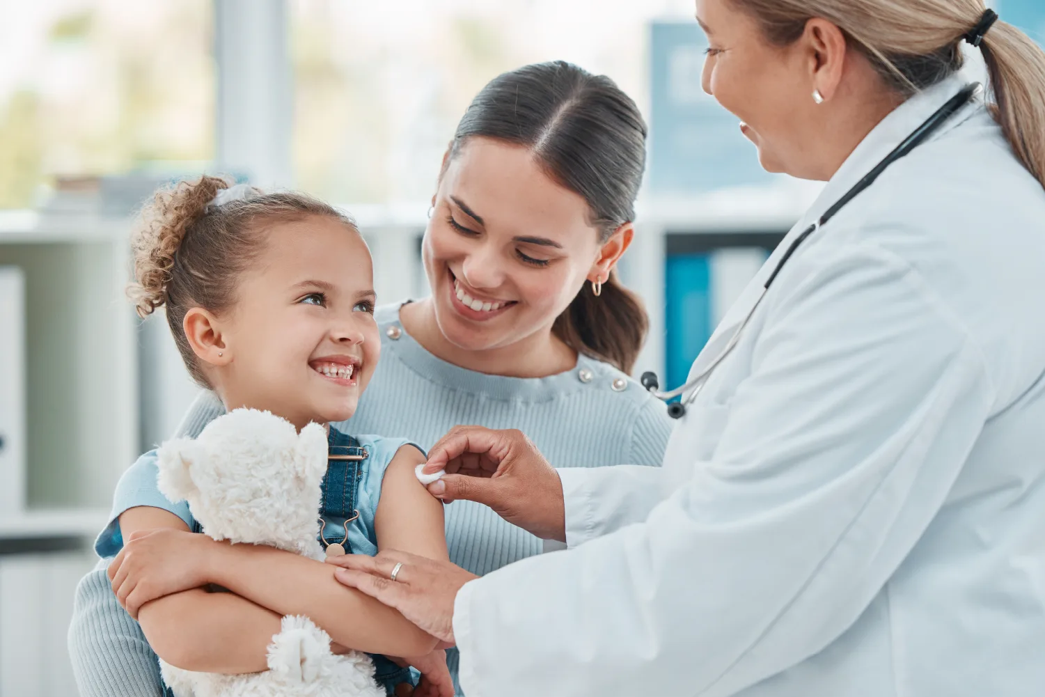 A pediatric provider examining a young patient held by their parent